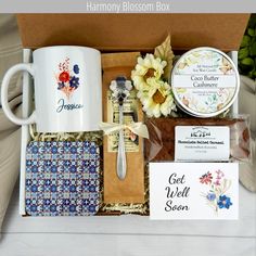 an assortment of items in a box including coffee mugs, tea bags and cards