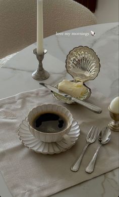 a cup of coffee sitting on top of a table next to a plate with cake