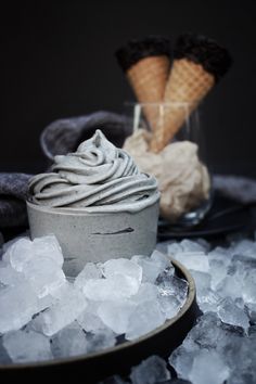 two ice cream cones sitting on top of an ice bucket filled with ice cubes