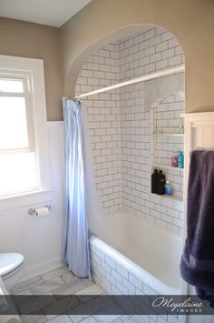 a bath room with a toilet and a bath tub next to a shower head mounted on a wall