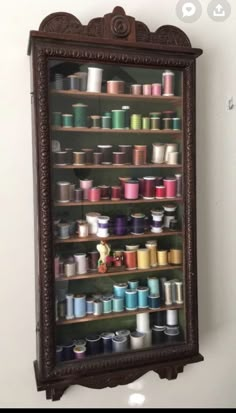 an old wooden shelf filled with lots of spools of thread on top of it