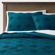 a bed with teal blue comforters and pillows on it's headboard