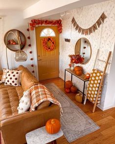 a living room filled with lots of furniture next to a yellow door and pumpkins on the floor