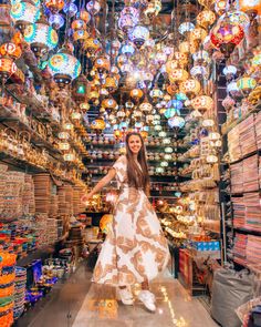 a woman standing in the middle of a store filled with lots of lights and ornaments