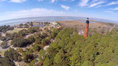 an aerial view of a light house in the middle of some trees near water and land