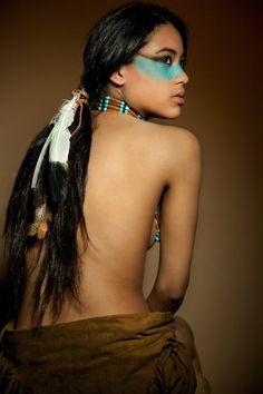 a woman with blue makeup and feathers on her back