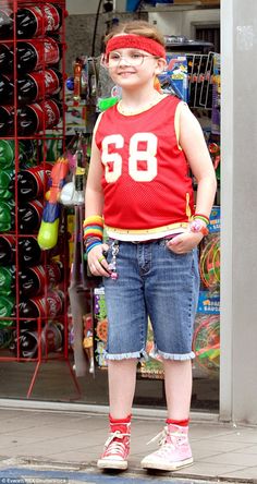 a young boy standing in front of a store with his hands on his hips and wearing glasses