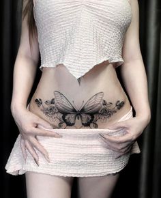 a woman with tattoos on her stomach and butterfly tattoo on the side of her belly