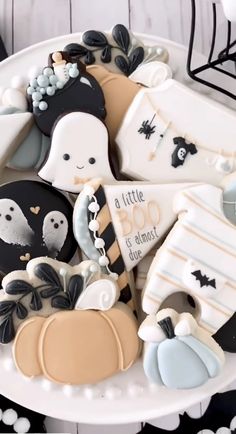 decorated cookies in the shape of halloween decorations on a white plate with black and white accents