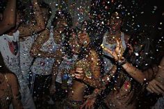 group of people throwing confetti on each other in the air at a party