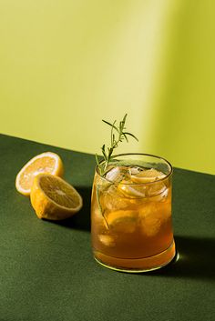 a glass filled with lemonade next to sliced oranges on a green counter top