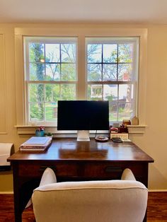 a desk with a computer on it in front of two windows