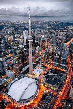 an aerial view of a city at night with lights on and tall buildings in the background