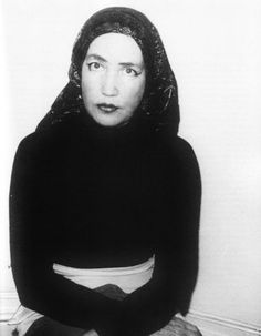 black and white photograph of a woman sitting on the floor in front of a wall