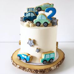 a birthday cake with cars and stars on the top is sitting on a tree stump