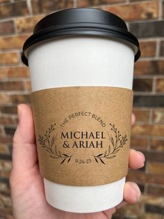 a person holding up a coffee cup with the label for stevens & morgan on it