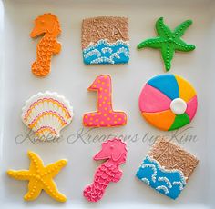 decorated cookies in the shape of numbers and seashells on a white platter