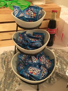 three tiered trays filled with candy and soda on a table next to glasses