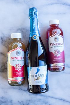 three bottles of syrup sitting on top of a marble counter