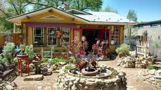 a small yellow house with lots of plants in the front yard and landscaping around it