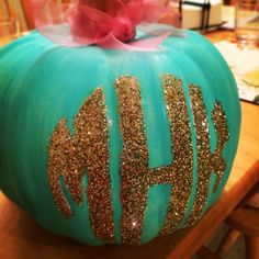 a painted pumpkin with gold glitters and a pink bow on it's top