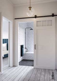 an open door leading to a bathroom with white brick walls and wood flooring in the background