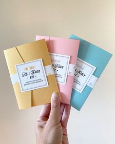 a hand holding four different colored envelopes