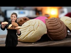 a woman holding a plate full of cookies and pastries in front of a pile of baked goods