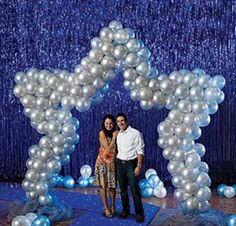 a couple standing in front of a star shaped balloon arch with balloons attached to it