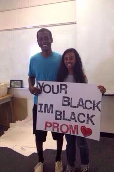 two people holding a sign that says your black i'm black prom