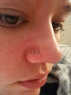 a close up of a woman with a nose piercing on her nose and looking at the camera