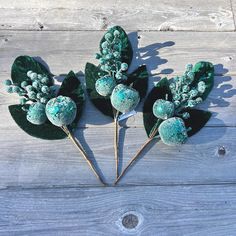 three small green plants with leaves on top of wooden planks, one is made out of glass beads