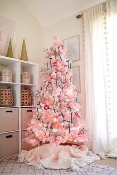 a pink christmas tree is decorated with ornaments