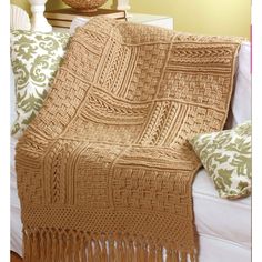 a crocheted blanket sitting on top of a bed next to pillows and a lamp