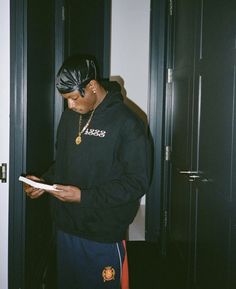 a man in a black hoodie is looking at a piece of paper while wearing a bandana