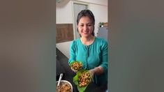 a woman holding two plates with food on them in front of a bowl and spoon