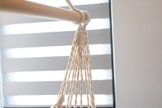 a hammock hanging from a wooden pole in front of a window with blinds