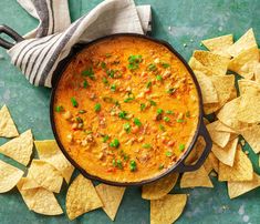 a skillet filled with chili and tortilla chips on a green counter top