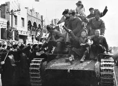 an old black and white photo of people on top of a tank in the street