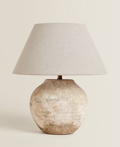 a white vase with a light on top of it next to a lampshade