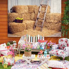 an outdoor area with hay bales, chairs and flowers on the ground in front of it