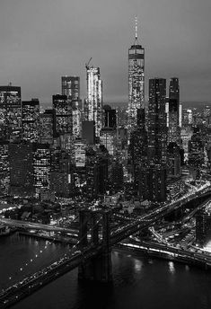 black and white photograph of the city skyline at night with bridge in foreground, new york city