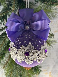 an ornament hanging from a christmas tree decorated with purple and white laces