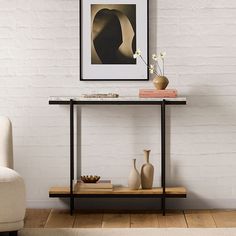 a table with two vases on it in front of a white brick wall