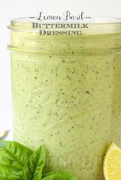 a mason jar filled with pesto sauce next to fresh basil leaves and a slice of lemon