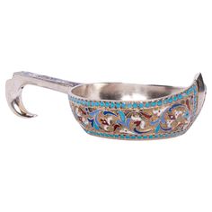 a silver and blue metal bowl with an ornate design on the side, holding a hammer