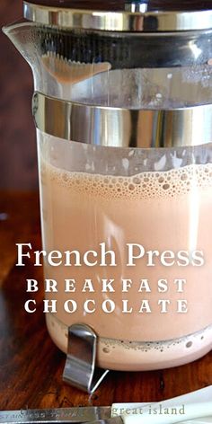 a french press coffee maker with the words breakfast chocolate in front of it on a wooden table