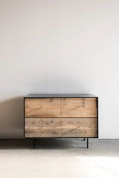 a wooden dresser sitting next to a white wall in a room with concrete flooring