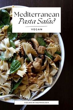 a white bowl filled with pasta and spinach