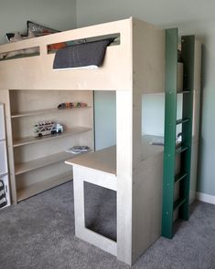 there is a loft bed with a desk underneath it and shelves below the top bunk